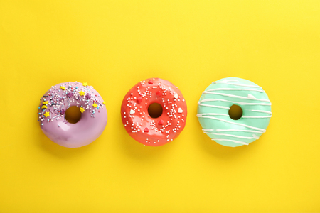 Tasty donuts with sprinkles on yellow paper backgroundの写真素材