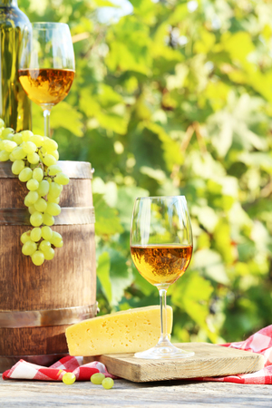 Grapes and wine in glasses with cheese and bottle on wooden tableの写真素材