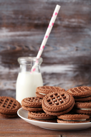 Chocolate cookies with bottle of milk on brown wooden tableの写真素材