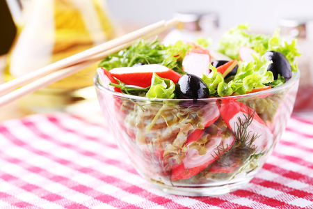 Salad with crab sticks, olives and lettuce in a bowlの写真素材