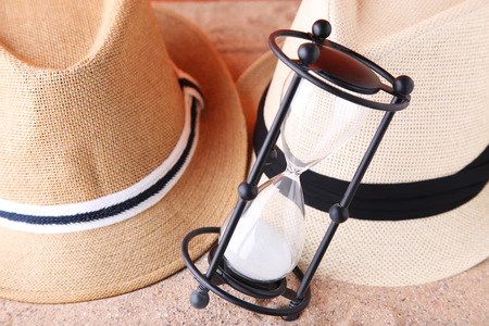 Black hourglass with hats on the beach sand