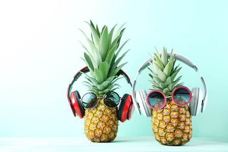 Ripe pineapples with sunglasses and headphones on mint backgroundの写真素材