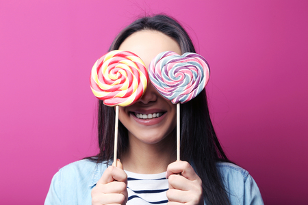 Young woman with lollipop on pink backgroundの写真素材