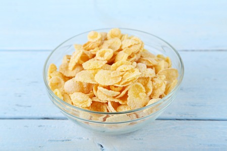 Cornflakes in bowl on blue wooden table