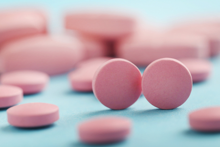 Heap of pink pills on blue backgroundの写真素材