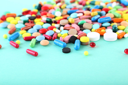 Different colorful pills on mint background