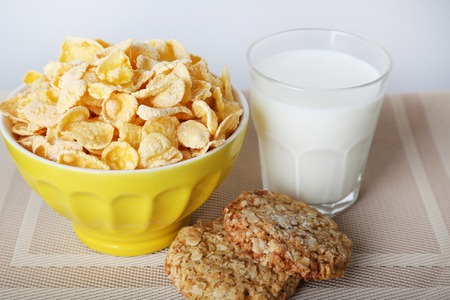 Cornflakes in bowl with glass of milk and cookies