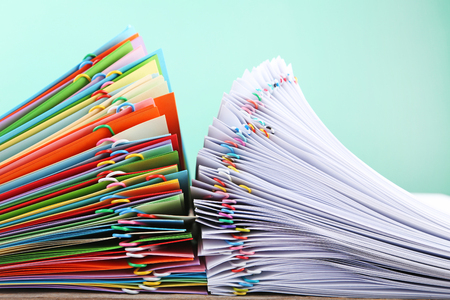 Stack of colored and white papers with paperclips on wooden tableの写真素材