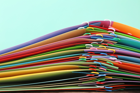 Stack of colored papers with paperclips on mint background