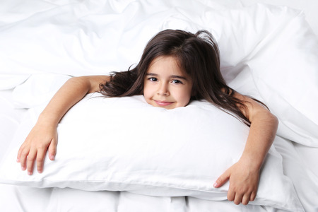 Beautiful little girl sleeping in white bedの写真素材