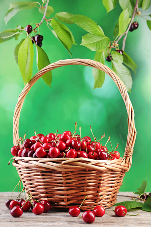 Sweet cherries in basket on wooden tableの写真素材
