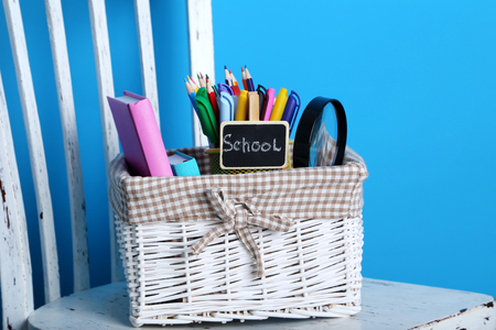 School supplies in the basket on white wooden chairの写真素材