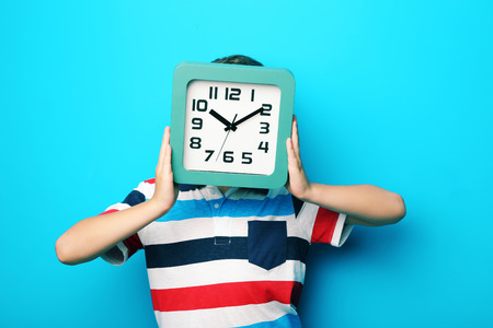 Young boy with clock on blue backgroundの写真素材