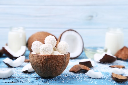 Coconuts with candies on blue wooden tableの写真素材
