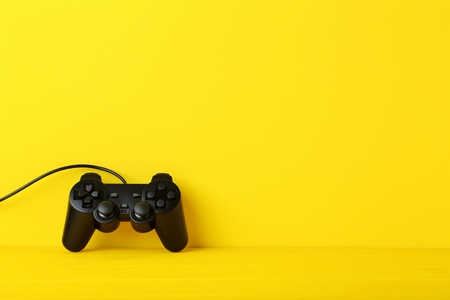 Black joystick on a yellow wooden table