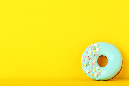 Tasty donut with sprinkles on yellow backgroundの写真素材