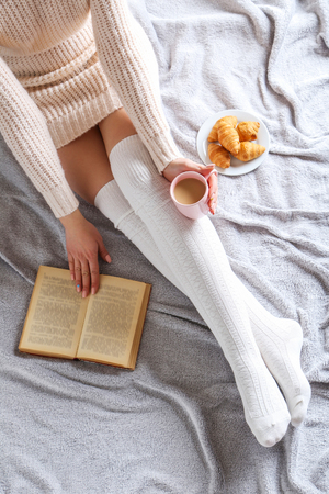 Woman with cup of coffee sitting on the bedの写真素材