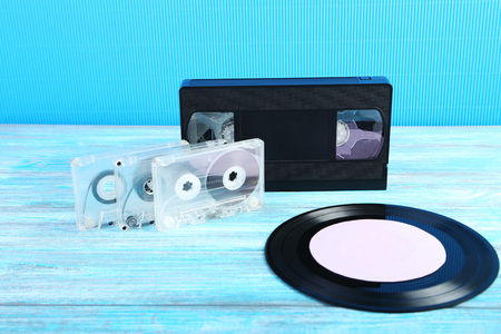 Vinyl record with video and music cassette tapes on wooden tableの写真素材