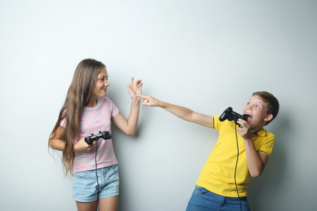 Young boy and girl with joysticks on grey backgroundの写真素材