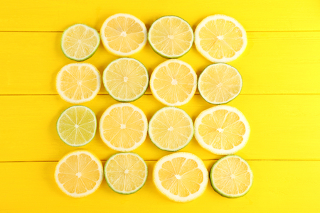 Slices of limes and lemons on yellow wooden tableの写真素材
