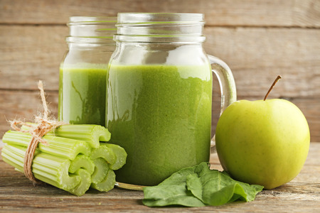 Bottles of juice with celery and apple on grey wooden tableの写真素材