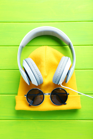 Headphones with yellow hat and sunglasses on a green wooden tableの写真素材