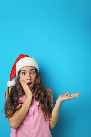 Portrait of young woman in santa hat on blue backgroundの写真素材