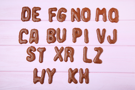 Chocolate cookies alphabet on pink wooden tableの写真素材