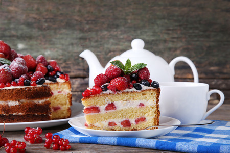 Homemade biscuit cake with berries and cup of tea on grey wooden tableの写真素材
