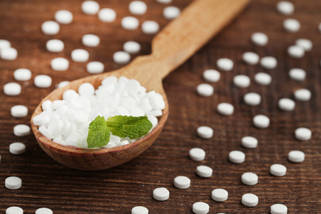 Sweetener tablets in wooden scoop with mint leaf on wooden tableの写真素材