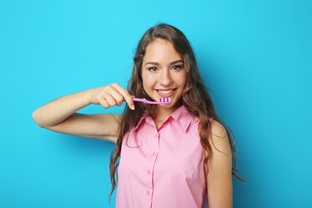 Portrait of young woman with toothbrush on blue backgroundの写真素材