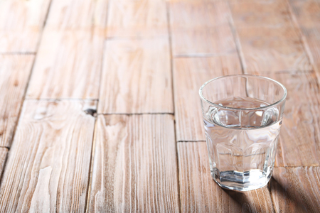 Glass with water on a brown wooden tableの写真素材