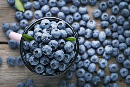 Ripe blueberries in pink mug on wooden table