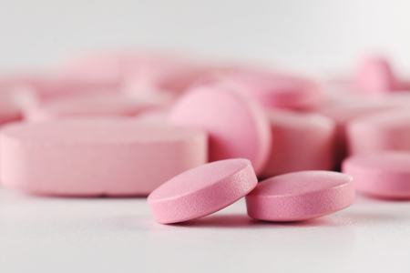Heap of pink pills on white backgroundの写真素材