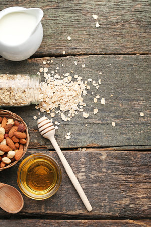 Oat flakes in bottle with nuts and milk on wooden tableの写真素材