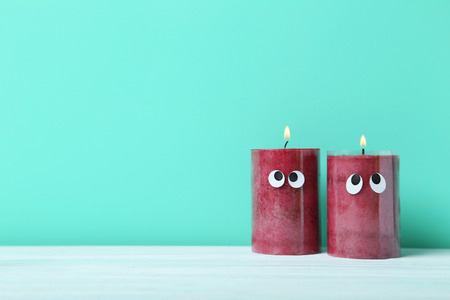 Burning candles with googly eyes on a green backgroundの写真素材