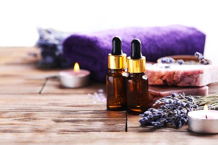 Lavender oil with soap and flowers on brown wooden tableの写真素材