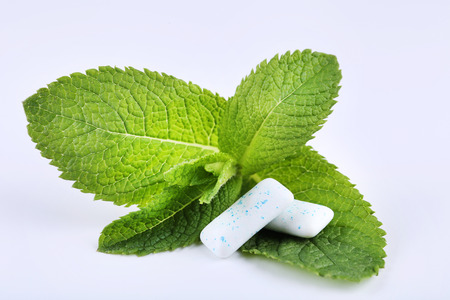 Chewing gums with mint leafs on white background
