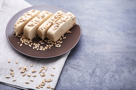 Tasty slices of halva in white plate on grey wooden tableの写真素材