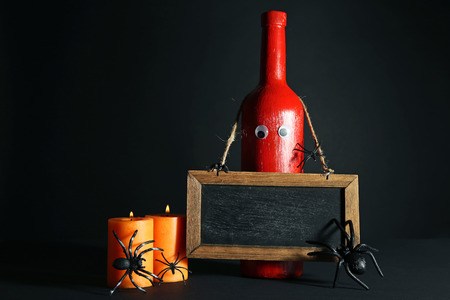 Red bottle with wooden frame, spiders and candlesの写真素材