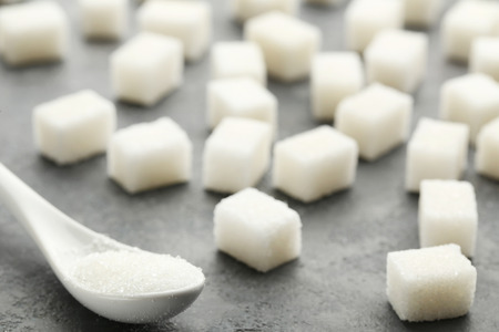 Sugar cubes with white spoon on grey wooden tableの写真素材