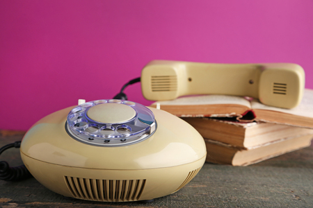 Beige retro telephone with books on grey wooden tableの写真素材