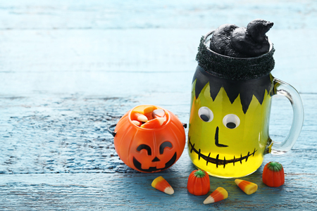 Halloween jelly in glass jar with candies on blue wooden tableの写真素材