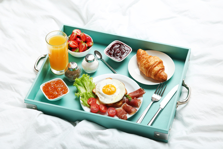 Tasty breakfast in bed on wooden trayの写真素材
