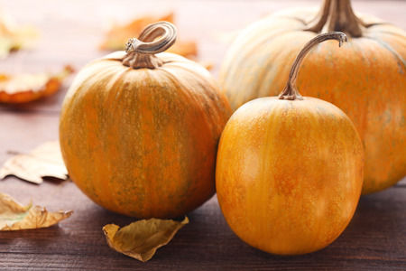 Orange pumpkins with dry leafs on wooden tableの写真素材