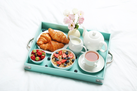 Tasty breakfast in bed on wooden trayの写真素材