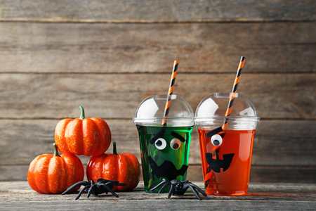 Halloween cocktail in plastic cups with pumpkins on grey wooden tableの写真素材