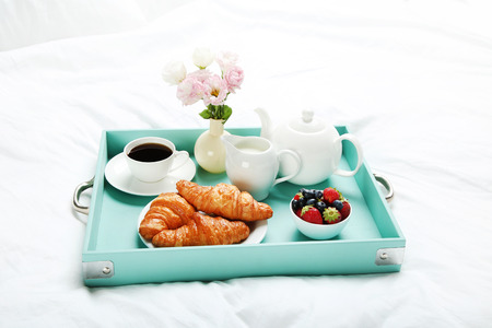 Tasty breakfast in bed on wooden trayの写真素材
