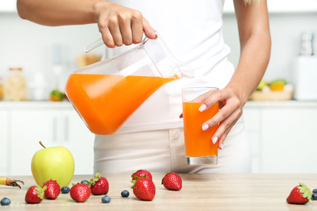 Young woman pouring juice in glassの写真素材