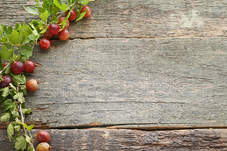 Ripe gooseberries fruit with leafs on wooden tableの写真素材